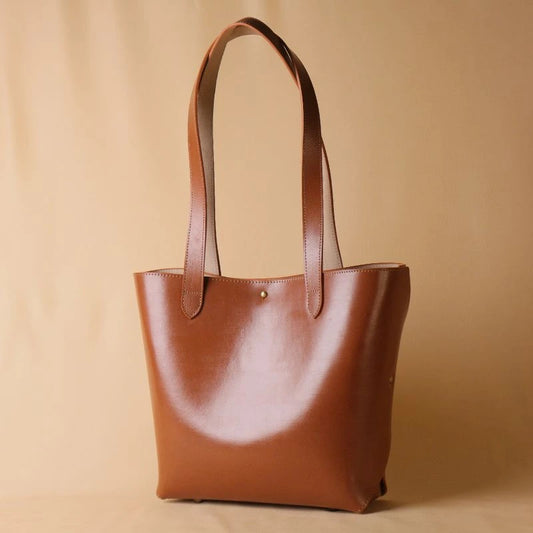 Perspective view of a tan leather tote handbag for women without zip